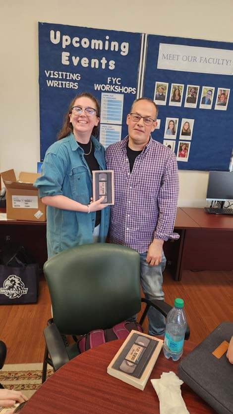 Woman and man holding a book, posing for a photo
