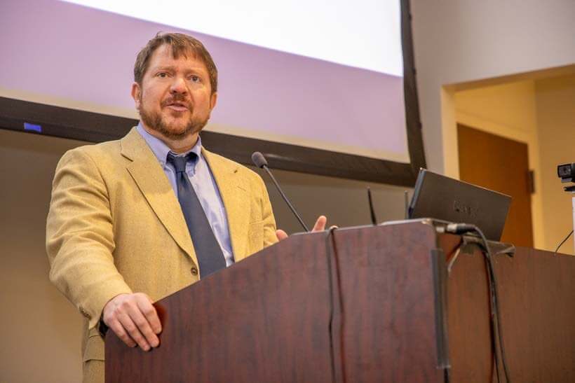 Man in suit and tie speaks at podium