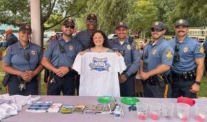 Student holding National Night Out shirt in front of six police officers.