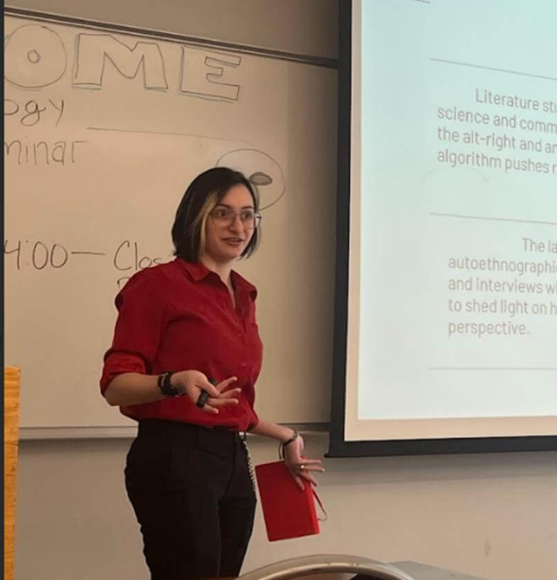 Student delivering a presentation while holding a red book in her hand