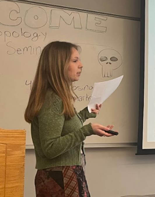 Student delivering a presentation while holding a remote and piece of paper in her hands