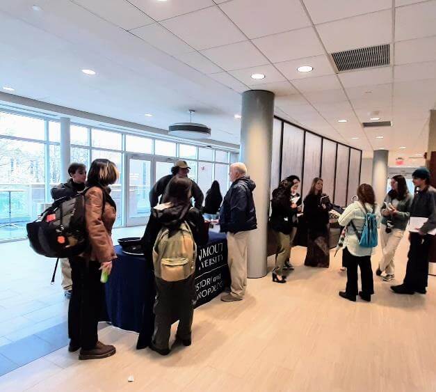 People in a hall crowding around a table for Monmouth University's Department of History and Anthropology