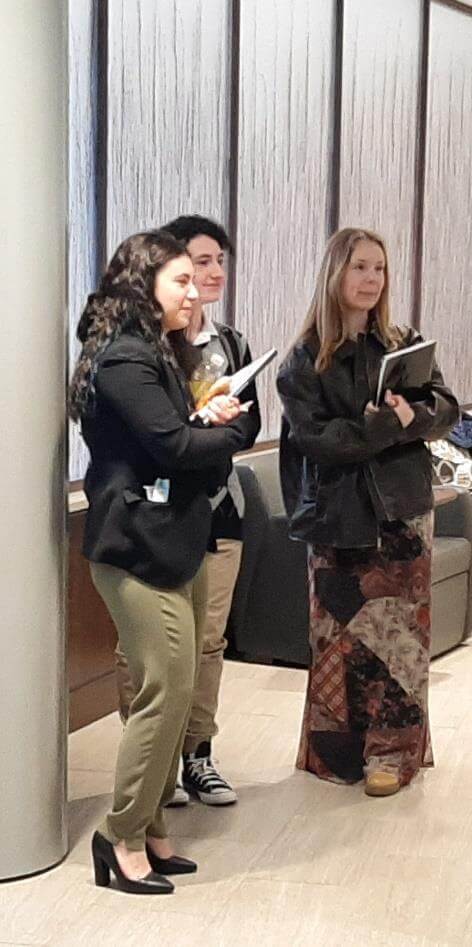 Three people holding notebooks while looking onward