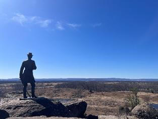 Statue of a soldier, standing a top of a cliff and looking out toward the plains.