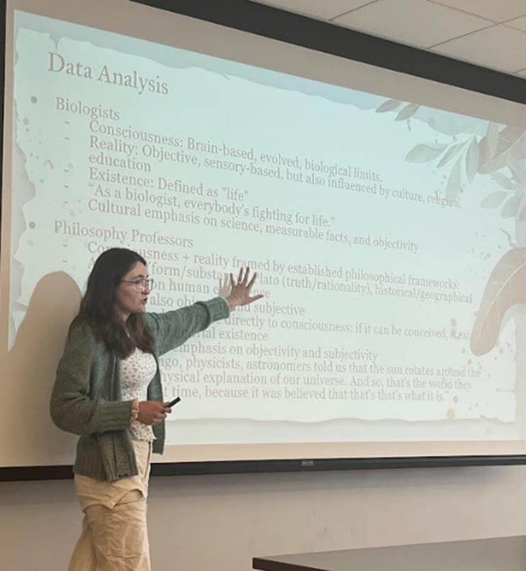 Student presenting power point presentation. Slide is about Data Analysis between Biologists and Philosophy Professors