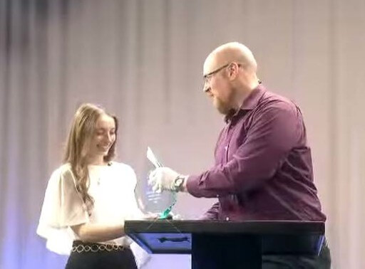 Man presenting woman with a glass trophy