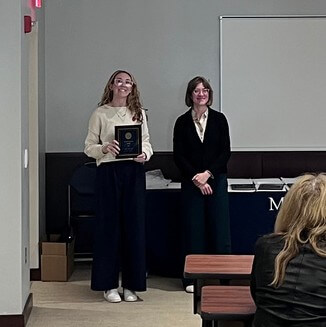 Student standing next to teacher with award plaque