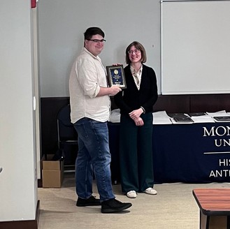 Student standing with award plaque next to woman