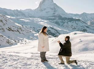 Man proposing to woman in snowy mountainscape.