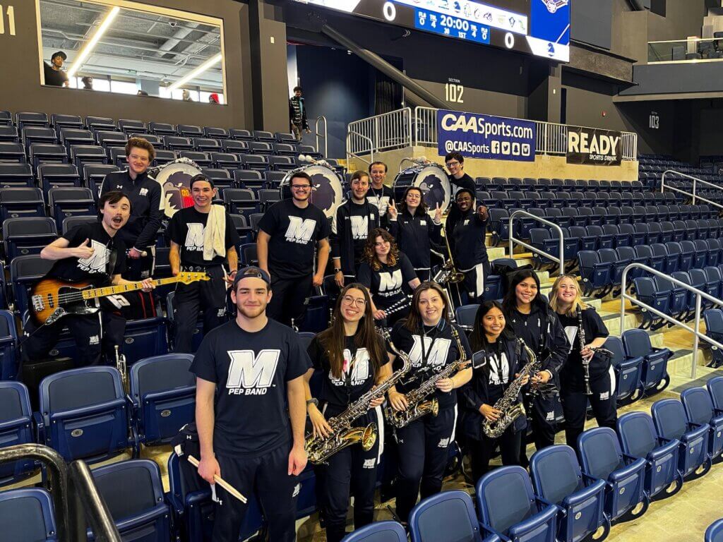 Pep Band in posing for photo in spectator stands