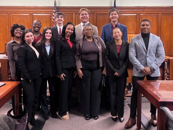 Professionals in suits standing in court room.