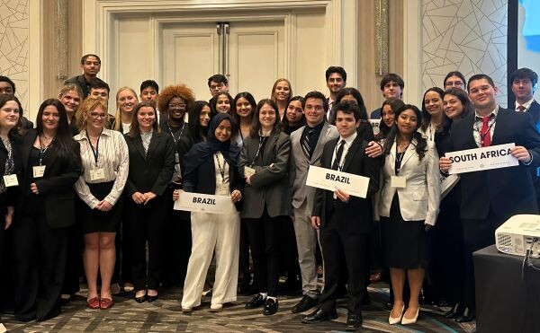 Young adults in suits holding signs with the names of countries on them.