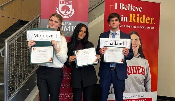 Three students in professional attire holding certificates