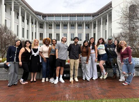 Students posing for photo in front of large building with columns