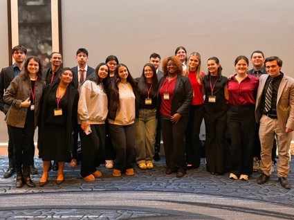 Large group of adults, some in suits, some in casual wear, and some with conference lanyards.