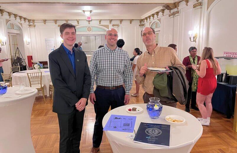 Three men near table posing for photo