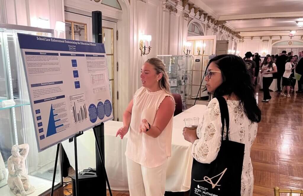 Two women observing poster presentation in hall