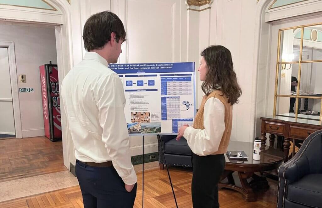 Woman and man speaking with each other near poster presentation