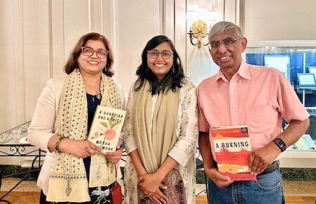 Megha Majumdar standing beside a man and a woman, each of whom are holding one of her books.