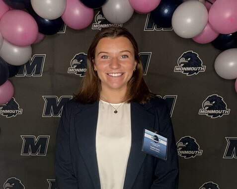 Woman near balloons, Monmouth University branding behind her