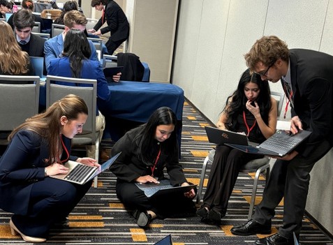 Conference goers sitting down, consulting laptops