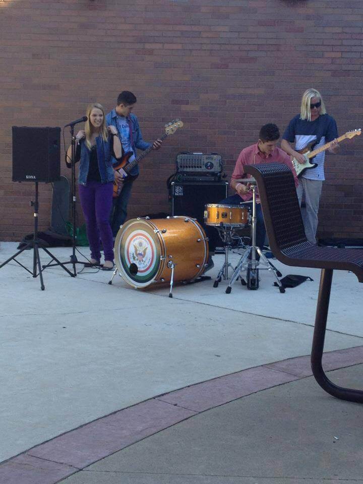 Band playing drums, guitars and vocals in student center