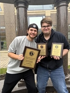 Two students holding award under Business School columns