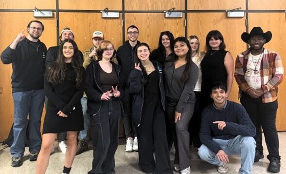 Debaters posing for a group photo, one wearing a cowboy hat
