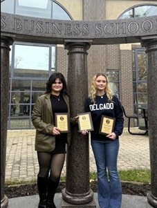 Two students holding award under Business School columns
