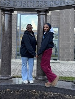 Two students posing for photo under Business School columns
