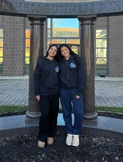 Two students posing for photo under Business School columns