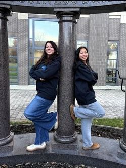 Two studentsleaning against Business School columns