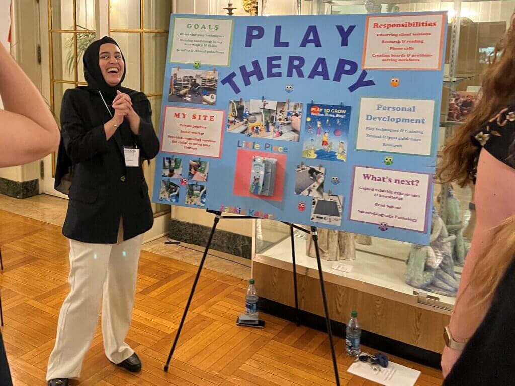 Student presents her poster about play therapy to conference attendees.  