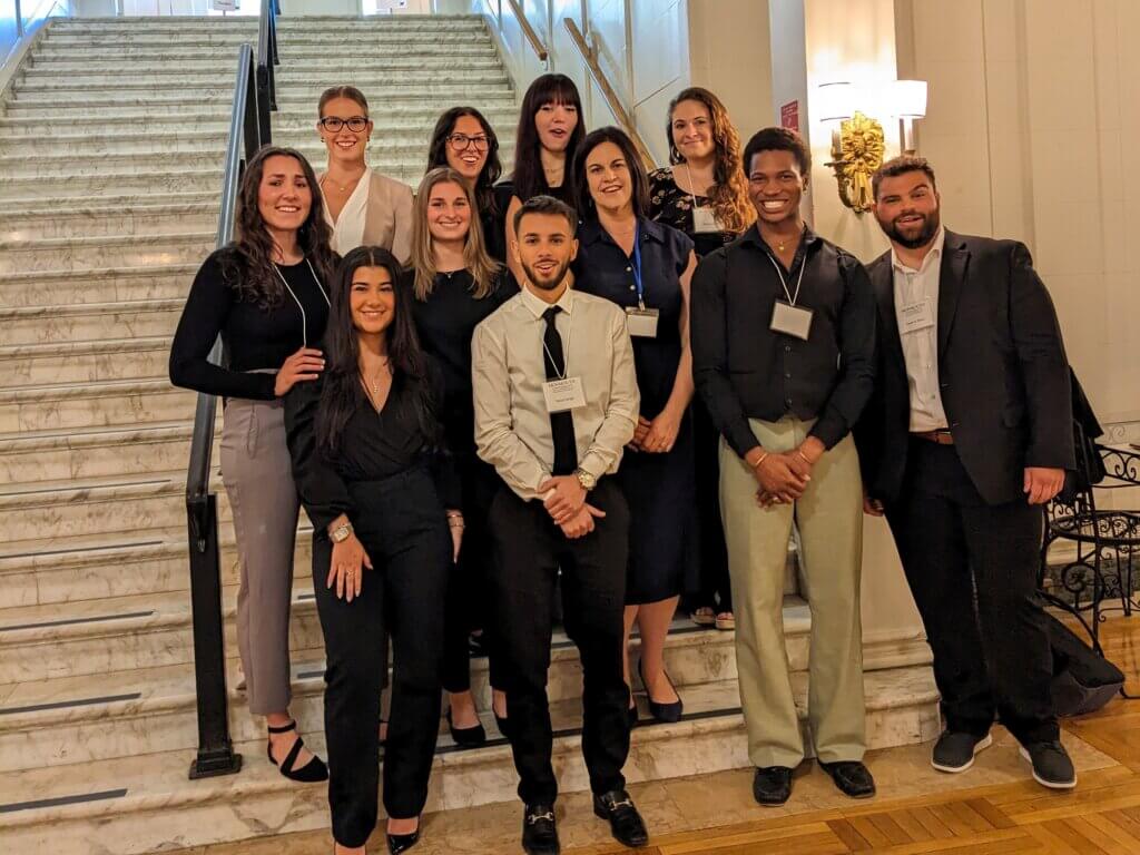 A group of students posing in front of a staircase in the Great Hall.