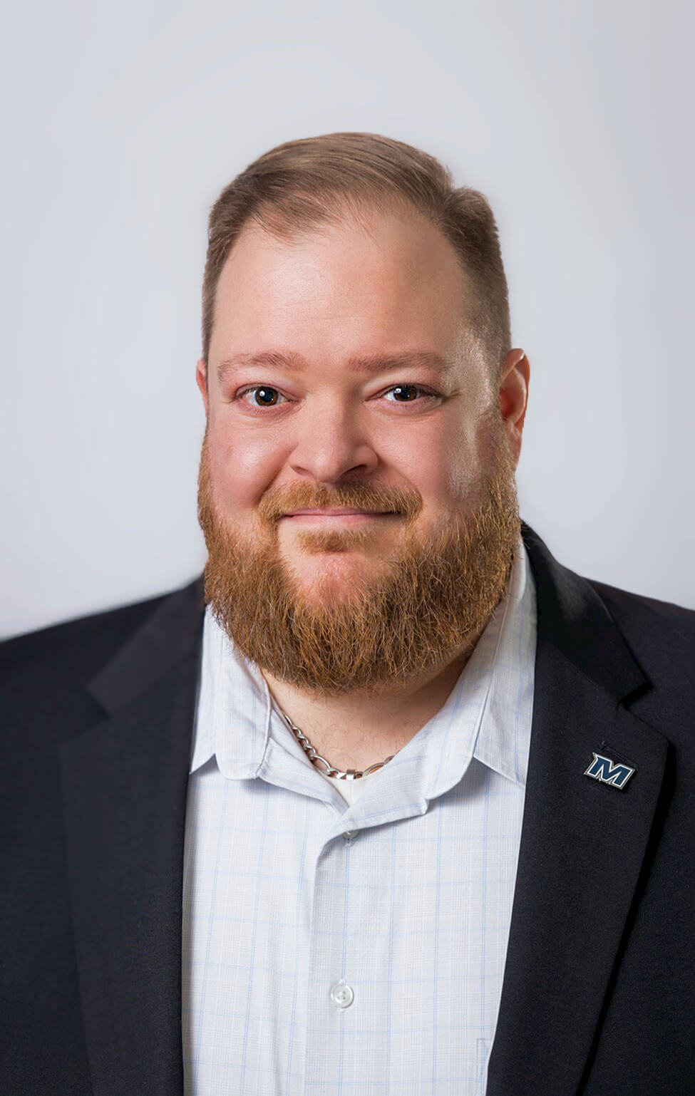 Headshot of Joe Palazzolo in a suit wearing the Monmouth University spirit logo as a badge on his suit jacket.