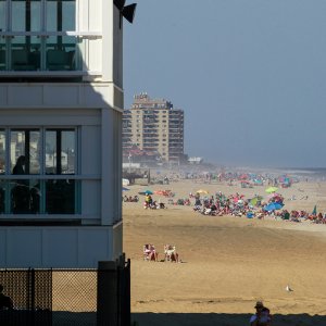 A sandy beach streatching out for miles with some high buildings looking out over the ocean.