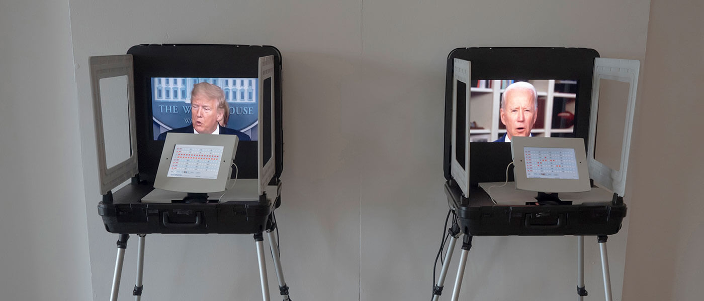 Photo shows two laptop computers each on separate chairs. the left screen shows Donald Trump talking while the right screen shows Joe Biden.