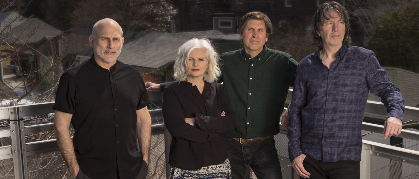 The Cowboy Junkies: Michael Timmins, Margo Timmins, Peter Timmins, and Alan Anton are standing on a balcony.