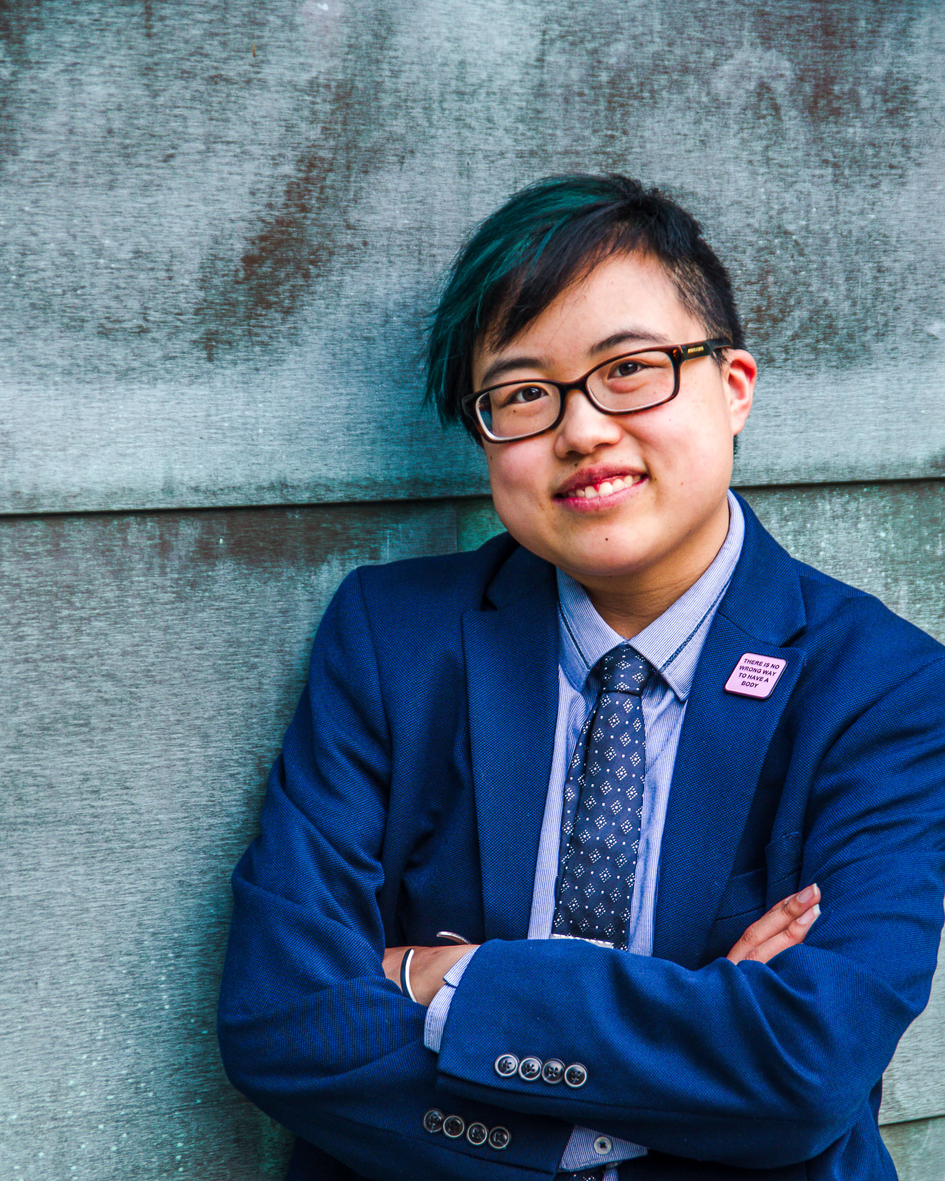 Photo of speaker Lydia X. Z. Brown. Individual wearing a blue suit in front of a teal wall