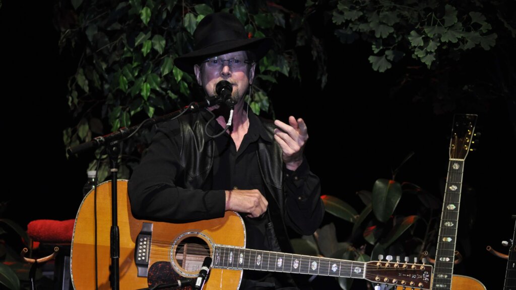 Roger McGuinn performing onstage.