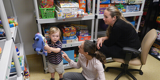 child playing with toy while interacting with two women