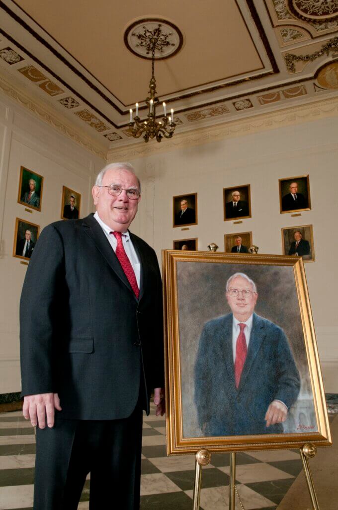 Shiavetti posing near a painted portrait drawn of him.