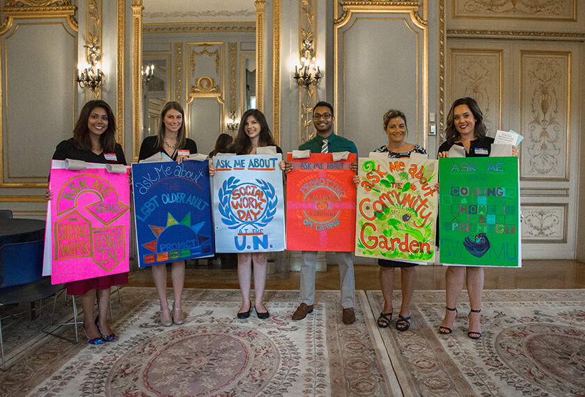 Students holding posterboards advertising different aspects of the School of Social Work.