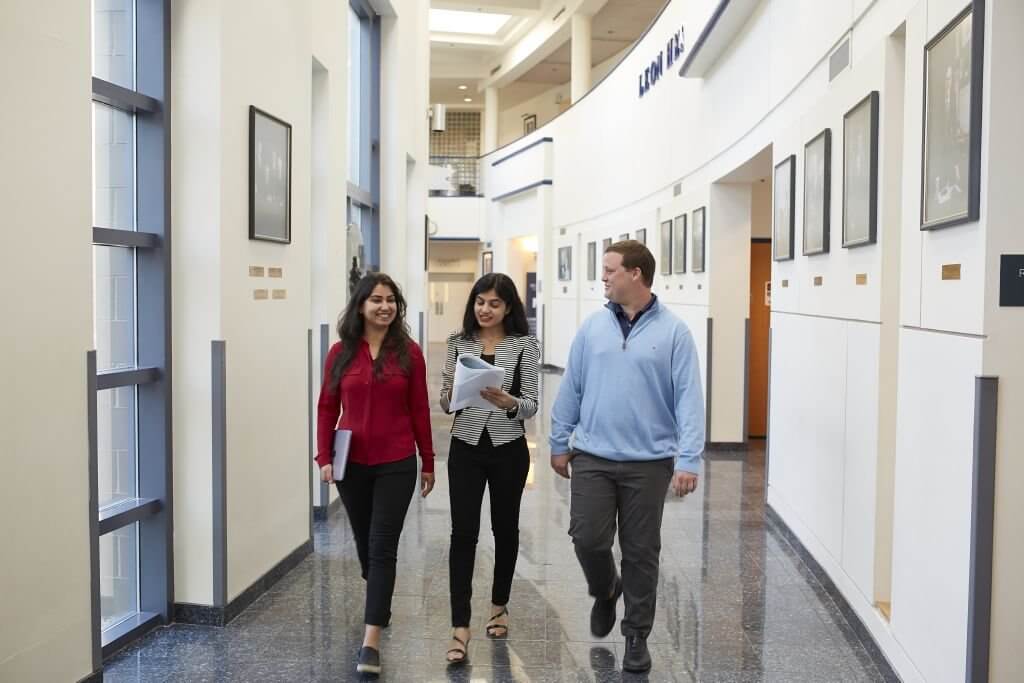 Business students walking through Bey Hall reviewing the MBA curriculum