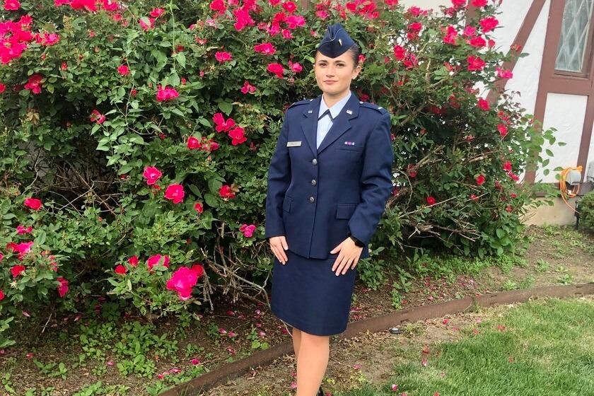 Cindy Rullo stands in Air Force uniform in front of a garden