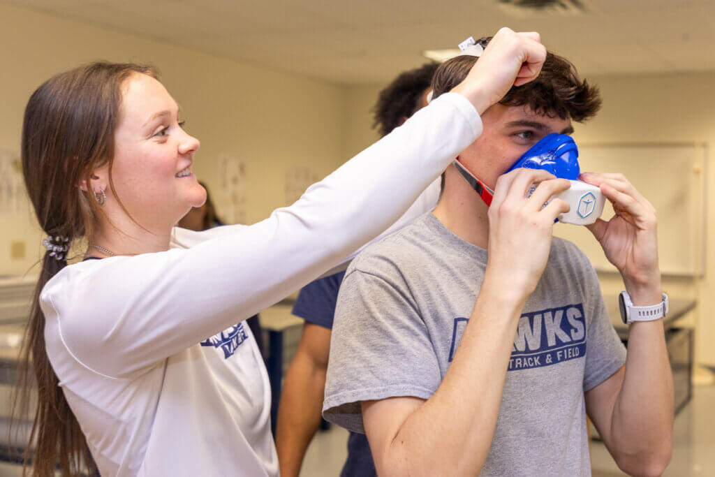 Woman putting a a mask labeled "VO2max" on a man's face