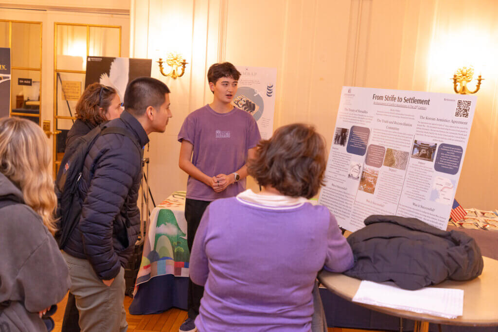 A student presenting a poster to attendees