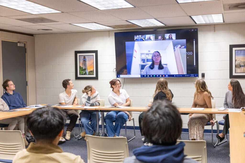 Attendees listen to a speaker on a television
