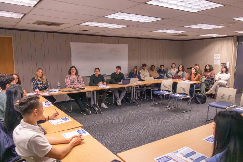 A room of seated attendees having a conversation 