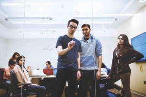 A student writing notes on a window in the School of Science building